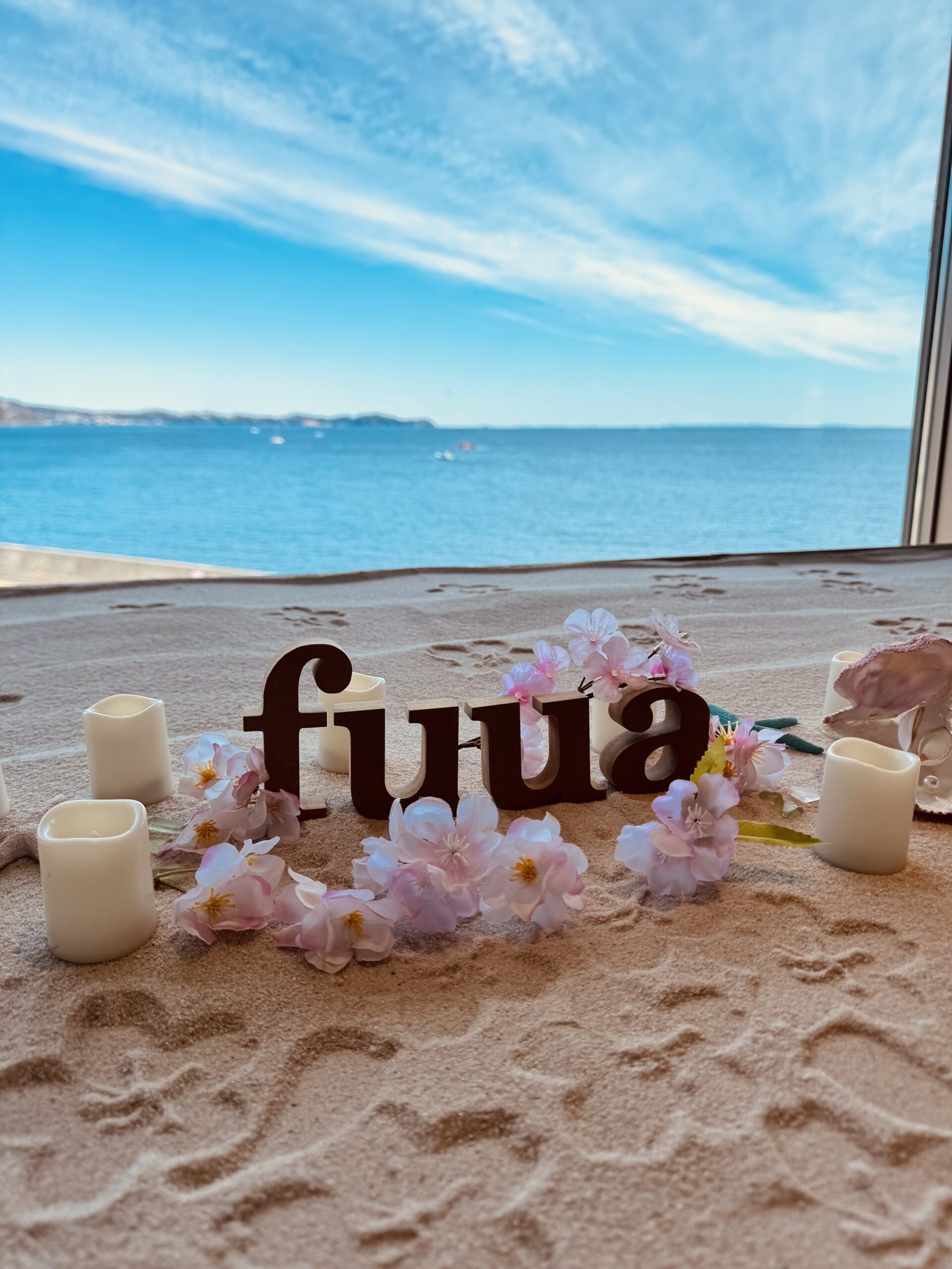 海の見える窓辺に飾られたFuuaの文字と花